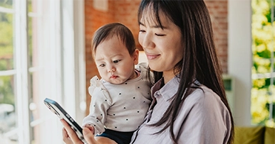 Mother holding a baby and looking at her phone